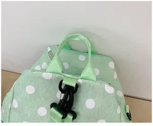Primo piano dettagliato dello zaino verde a pois che mostra la maniglia e le fibbie.