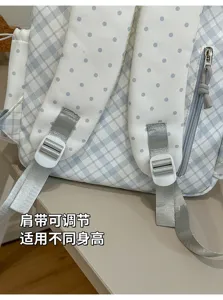 Gros plan sur des bretelles réglables, boucles blanches et tissu bleu clair à carreaux et pois