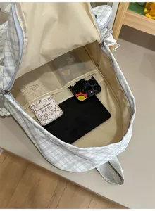 Vue rapprochée du sac à dos ouvert, avec doublure beige, poches intérieures et effets personnels