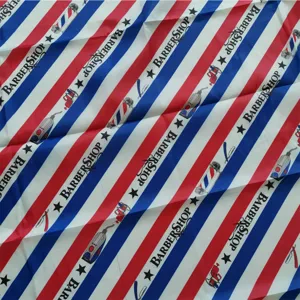 Professional salon barber cape detail showing classic red white blue stripes and scissor print.
