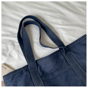 Vue de détail du grand sac cabas en denim bleu avec double poignée solide et belles coutures.