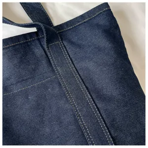 Vue détaillée du sac cabas en denim avec coutures contrastées et texture solide.