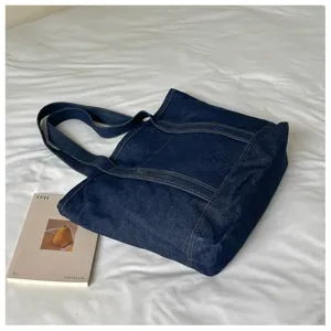 Gros plan sur le sac cabas en denim bleu foncé, coutures solides et texture résistante visible.