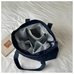 Grand sac cabas en denim avec doublure rayée et multiples poches intérieures pour le quotidien.