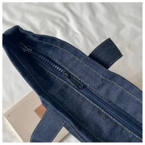 Détail de fermeture éclair du sac cabas en denim, toile bleu foncé robuste pour usage.