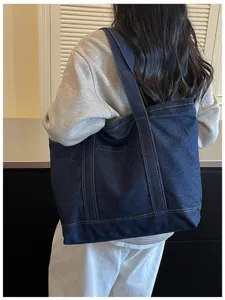 Vue détaillée du grand sac cabas en denim montrant des coutures solides et un usage quotidien.