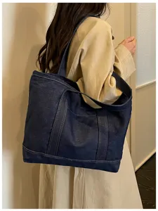 Vue détaillée d'un grand sac cabas en denim bleu foncé, style sac bandoulière quotidien.