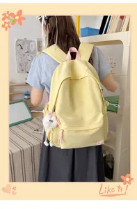 Korean style solid color backpack detail showing cute pink bow embroidery and soft fluffy pendant.