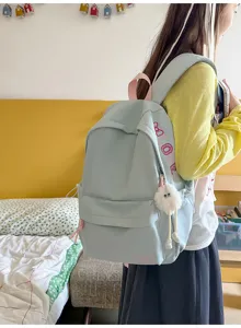 Detail view of light blue casual campus backpack with side print and cute plush pendant.