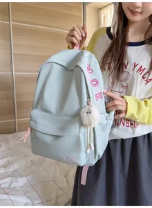 Cute pastel blue backpack detail showing sweet bow embroidery and fluffy plush charm for daily wear.