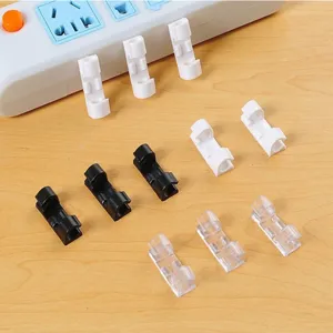 Close-up view of self-adhesive cable clips in white, black and transparent designs on a desk.