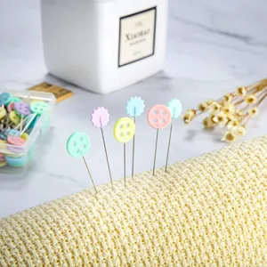 Detailed shot of colorful flower and button sewing pins inserted in fabric for tailoring.