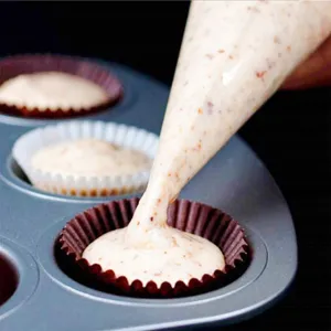 Primer plano detallado de la manga pastelera desechable llenando masa en el molde.