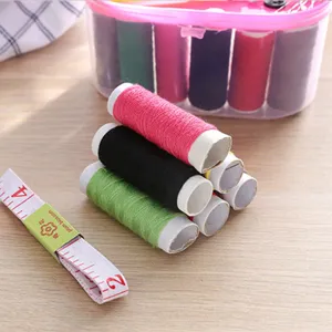 Boîte de couture portable à double couche avec bobines de fil colorées et ruban à mesurer.