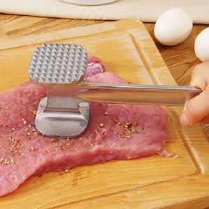 Close-up detail of the durable aluminum double-sided meat tenderizer in kitchen use.