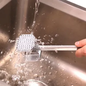 Detail view of a metal meat tenderizer hammer being washed with running water in a steel sink.