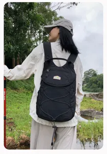 Vista detallada de la mochila negra para exteriores con cordón y bolsillo frontal al aire.