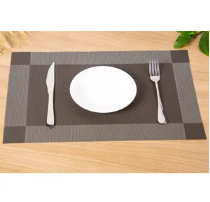 Vue détaillée du set de table en PVC tissé marron sur table en bois pour usage quotidien.