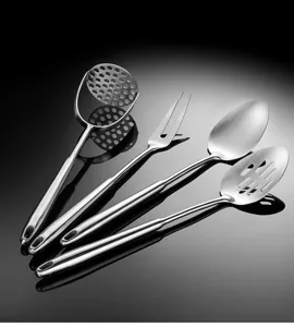 Dettaglio set di utensili da cucina in acciaio inox con schiacciapatate, forchetta e cucchiai.