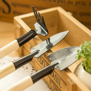 Close-up detail of mini garden tool set with wooden handles and metal rake and shovels.
