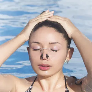 Primo piano chiaro dello stringinaso da nuoto in silicone indossato nell'acqua della piscina.
