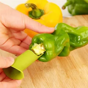 Close-up detail shot of green pepper corer tool in action, demonstrating core removal easily.