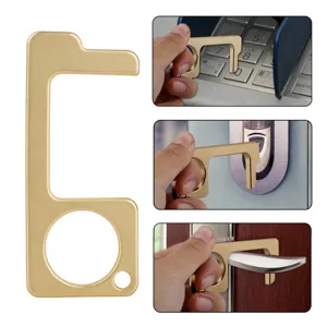 Detail view of brass touchless door opener and hygiene hand stylus tool for public buttons.