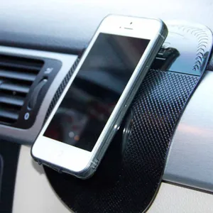 Detail shot of black carbon pattern silicone car dashboard anti slip mat holding smartphone securely.