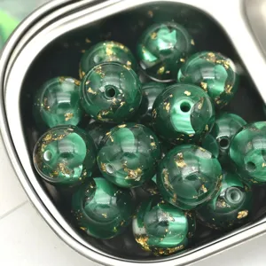 Vue détaillée de perles en résine nacrée vert foncé de 16mm avec feuille d'or pour loisirs créatifs.
