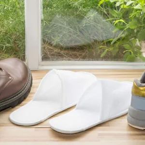 Detailed view of white disposable hotel slippers on wooden floor, soft and lightweight indoor