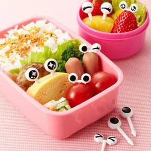 Detailansicht niedlicher Bento-Spieße mit Augen und Fruchtgabeln in einer rosa Brotdose.