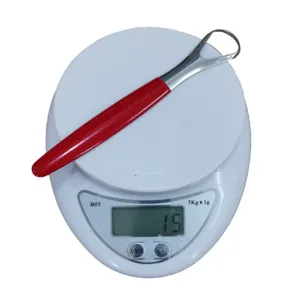 Stainless steel tongue scraper detail showing product weight on scale, oral hygiene tool.