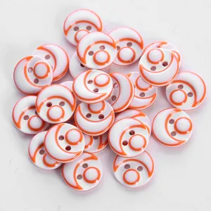 Close up detail of colorful resin buttons with two holes and orange crescent pattern for shirts.