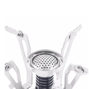 Close-up view of portable camping stove burner head with foldable metal legs and igniter.