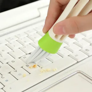 Primer plano detallado del cepillo de limpieza eliminando migas de la superficie del teclado.