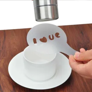Coffee stencil detail shot showing heart love cutout pattern over white cup and saucer set.