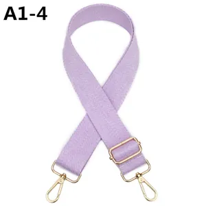 Primer plano de una correa de bolso ajustable en color morado claro con herrajes dorados.
