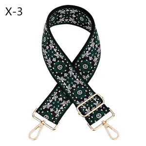 Detailed view of wide embroidered bag strap with ethnic patterns and gold hardware.