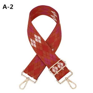 Detailed view of wide embroidered replacement bag strap with red argyle pattern and gold hardware.