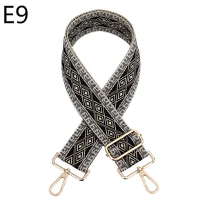 Detailed view of the ethnic geometric woven bag strap with adjustable gold metal hardware.