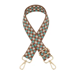Gedetailleerd overzicht van een bruine en turquoise geruite tasriem met gouden hardware.