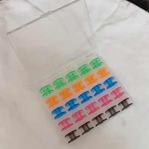 Caja de almacenamiento de plástico transparente llena de bobinas de costura coloridas, detalle.