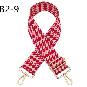 Detailed view of red and white houndstooth replacement bag strap with shiny gold metal hardware.