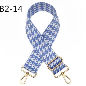 Blue white houndstooth bag strap detail with golden metal adjustable hardware and clasps.