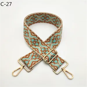 Detailed view of ethnic jacquard bag strap with adjustable gold metal hardware buckles.