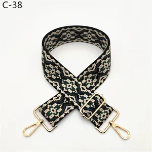 Detailed view of ethnic jacquard bag strap, black and green geometric weave with gold hardware.