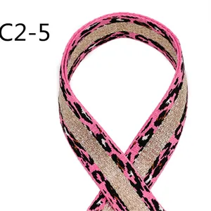 Closeup of ethnic style 3.8cm jacquard ribbon with pink leopard print and shimmering gold thread.