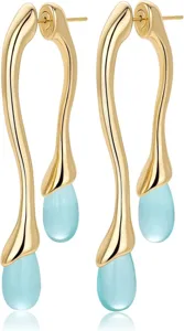 Gros plan détail de longues boucles d'oreilles dorées avec pendentifs goutte d'eau.