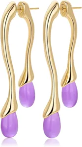 Gros plan détaillé de boucles d'oreilles pendantes vintage en laiton doré et goutte violette.