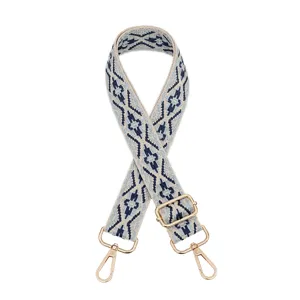 Detailed view of adjustable woven bag strap with ethnic geometric pattern and gold hardware.